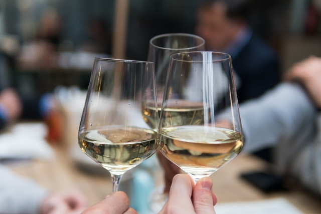 Close up of three people toasting with glasses of riesling